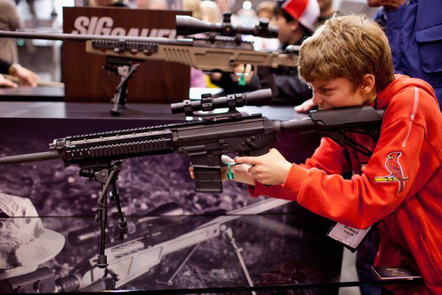 Billy Bitting Jr., 11, handles a SIG Sauer SIG556 semi-automatic rifle during the NRA Annual Meetings and Exhibits April 14, 2012 at America's Center in St. Louis, Missouri